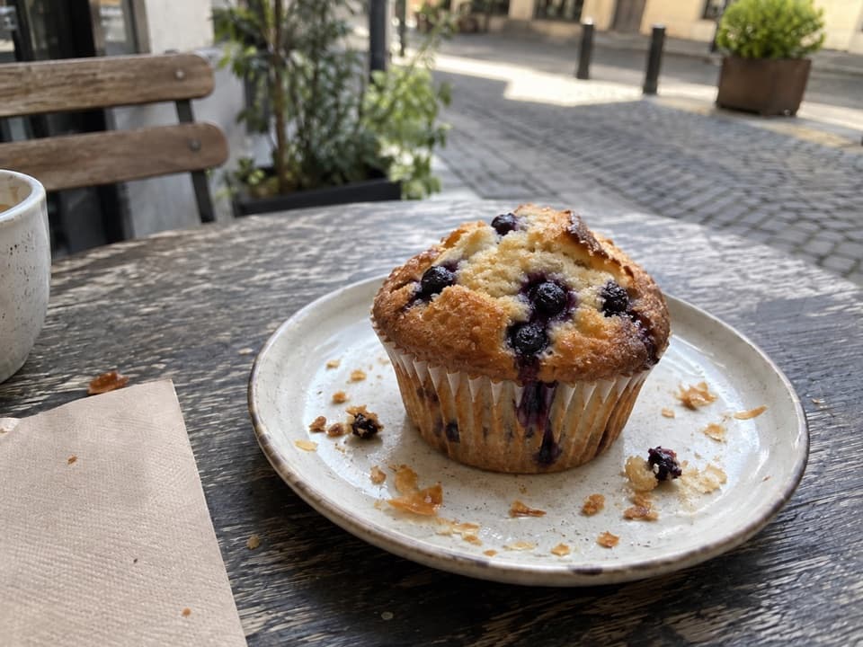 Blueberry muffin on a plate at an outdoor café